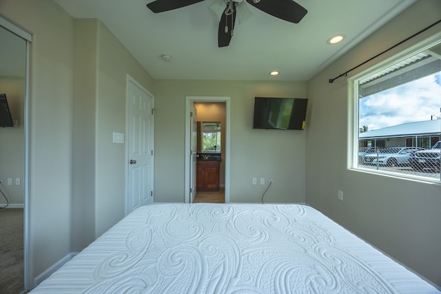 carpeted bedroom featuring connected bathroom, multiple windows, and ceiling fan