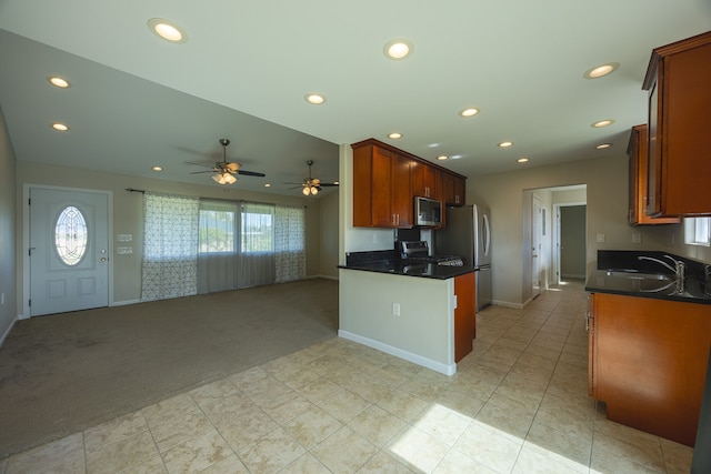 kitchen with light carpet, kitchen peninsula, stainless steel appliances, ceiling fan, and sink