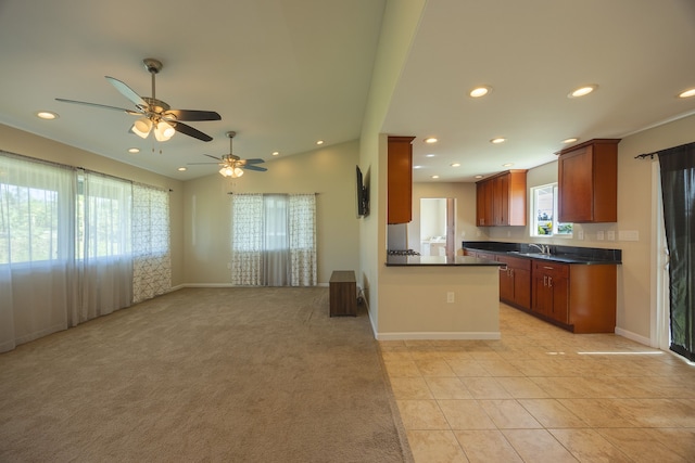 kitchen with kitchen peninsula, light tile patterned floors, ceiling fan, and a healthy amount of sunlight