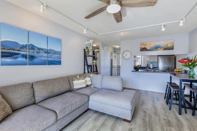 living room featuring a mountain view, ceiling fan, and light hardwood / wood-style flooring