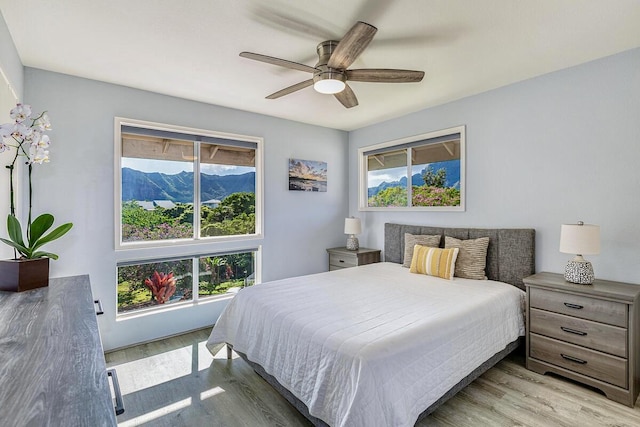 bedroom featuring ceiling fan, light wood-type flooring, and a mountain view