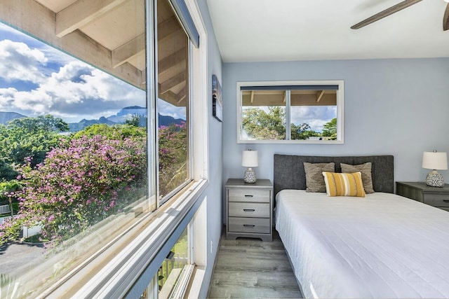 bedroom featuring ceiling fan, a mountain view, and light wood-type flooring