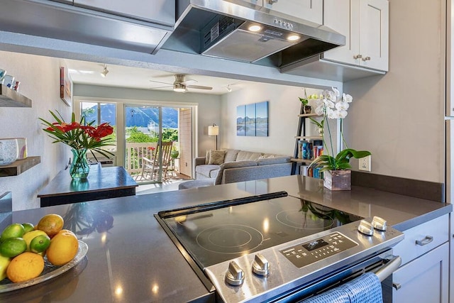 kitchen with white cabinetry, stove, ceiling fan, and range hood