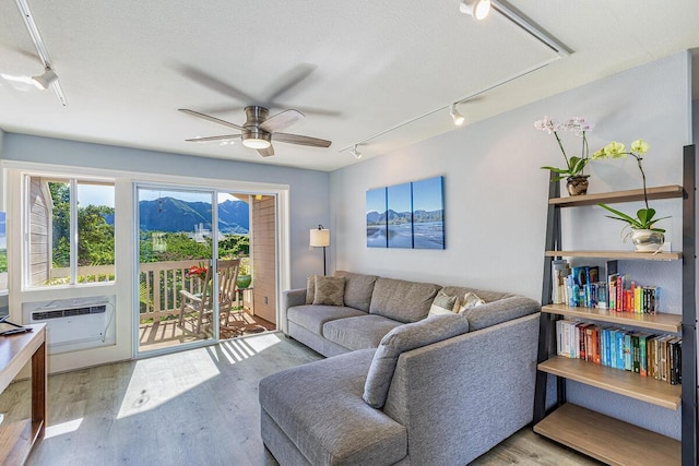 living room featuring ceiling fan, light hardwood / wood-style floors, and a mountain view