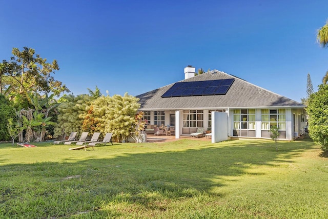 rear view of house featuring solar panels, a patio area, and a lawn