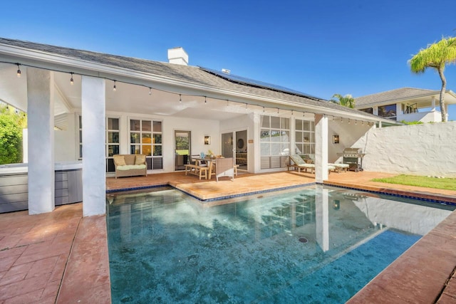 back of property with a fenced in pool, a patio area, outdoor lounge area, and solar panels