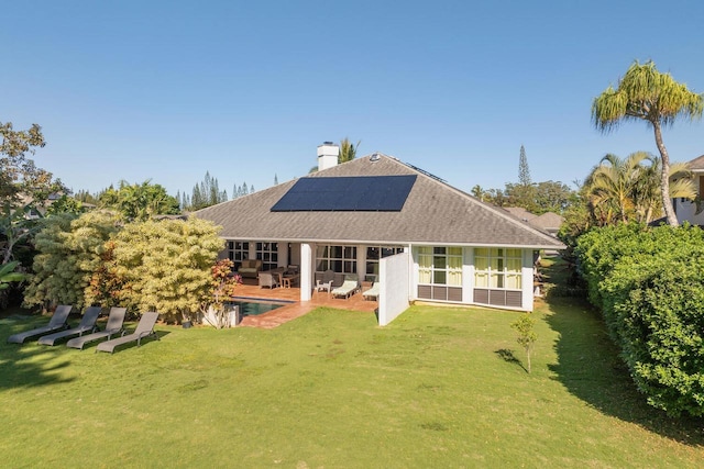 back of house featuring a lawn, solar panels, and a patio area