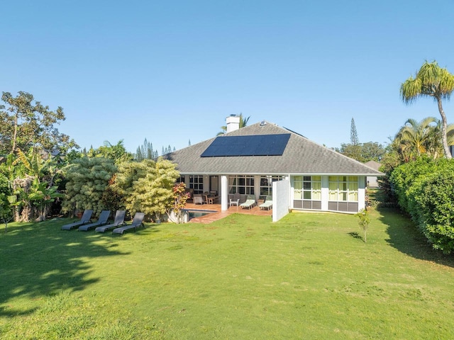 back of house with solar panels, a patio area, and a yard