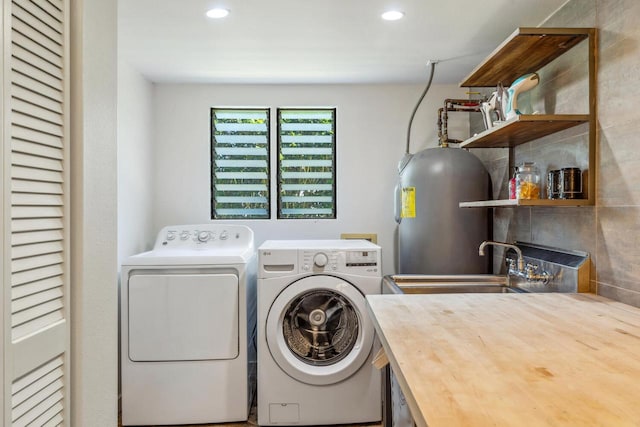 washroom with electric water heater, separate washer and dryer, and sink