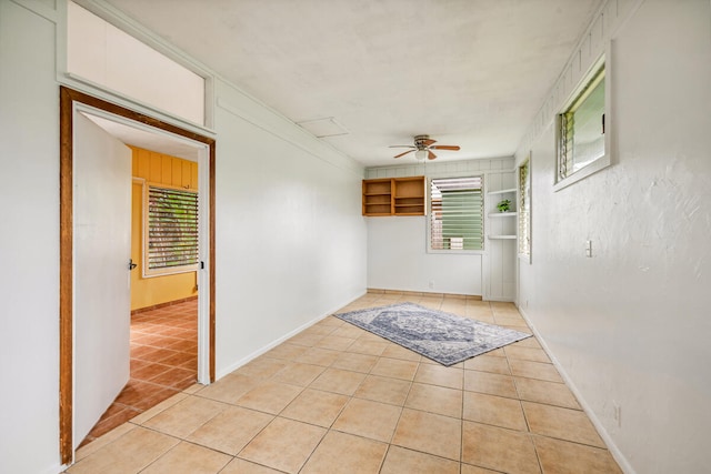 tiled empty room with a wealth of natural light and ceiling fan