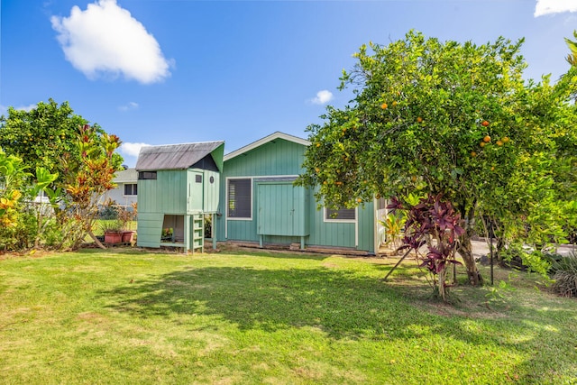 rear view of property with a storage shed and a yard