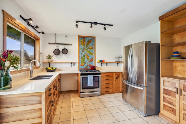 kitchen with appliances with stainless steel finishes, rail lighting, light tile patterned floors, and sink