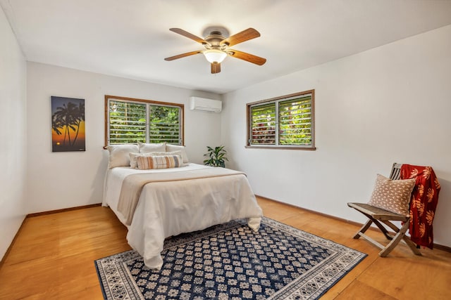 bedroom featuring hardwood / wood-style floors, ceiling fan, an AC wall unit, and multiple windows