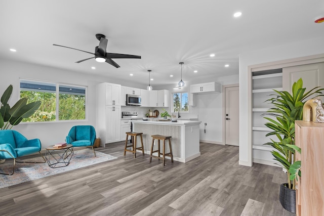 kitchen featuring white cabinetry, hanging light fixtures, a breakfast bar, a kitchen island, and appliances with stainless steel finishes