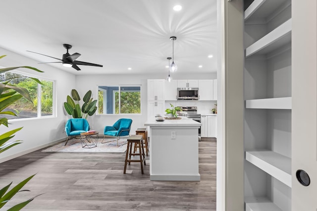 kitchen with ceiling fan, stainless steel appliances, light hardwood / wood-style floors, decorative light fixtures, and white cabinets