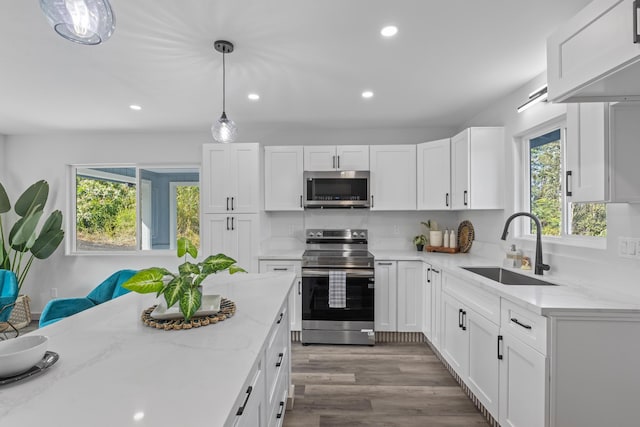 kitchen with pendant lighting, sink, light stone counters, white cabinetry, and stainless steel appliances