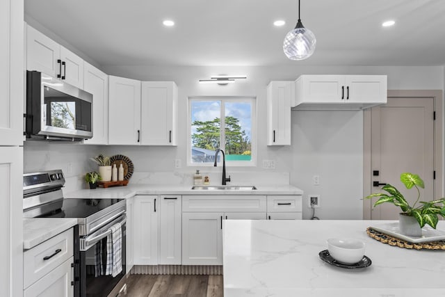 kitchen with white cabinetry, sink, stainless steel appliances, light stone counters, and pendant lighting