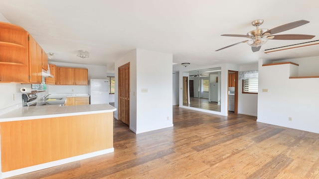 kitchen with white refrigerator, dark hardwood / wood-style floors, ceiling fan, tile counters, and kitchen peninsula