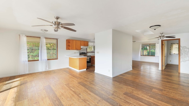 unfurnished living room featuring a skylight, ceiling fan, and dark hardwood / wood-style flooring