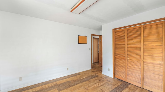 unfurnished bedroom with wood-type flooring and a closet