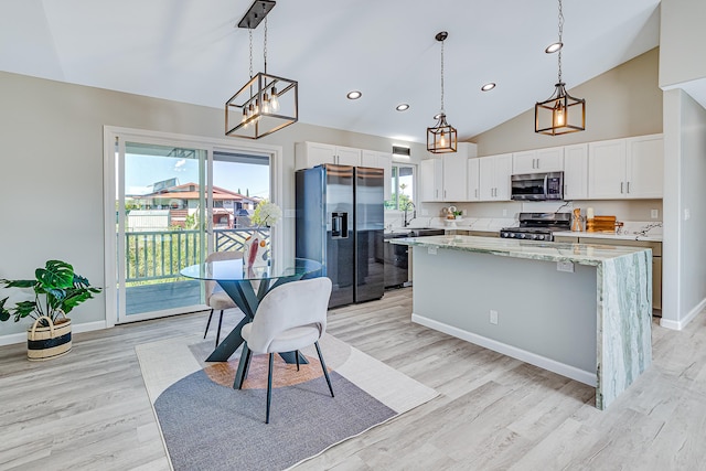 kitchen featuring refrigerator with ice dispenser, white cabinetry, gas range oven, and pendant lighting