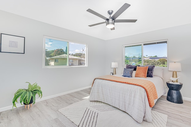 bedroom featuring multiple windows, ceiling fan, and light hardwood / wood-style flooring