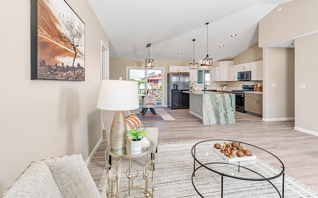 living room featuring sink, light hardwood / wood-style floors, and vaulted ceiling