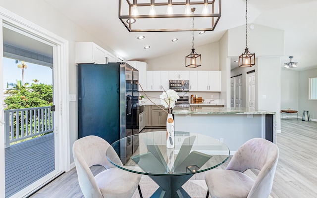 dining area with light wood-type flooring and lofted ceiling