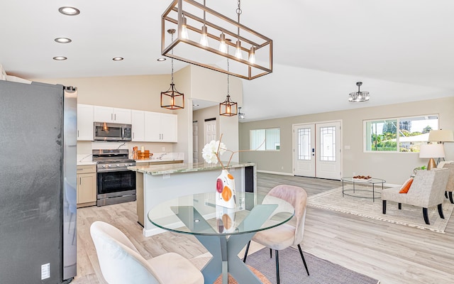 dining area with french doors, light hardwood / wood-style floors, and vaulted ceiling