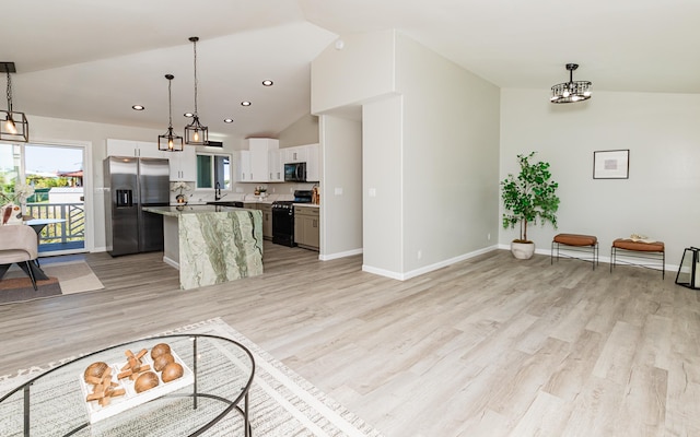 unfurnished living room featuring light hardwood / wood-style flooring, vaulted ceiling, and sink