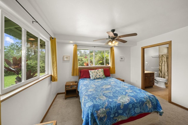 carpeted bedroom with connected bathroom, multiple windows, and ceiling fan