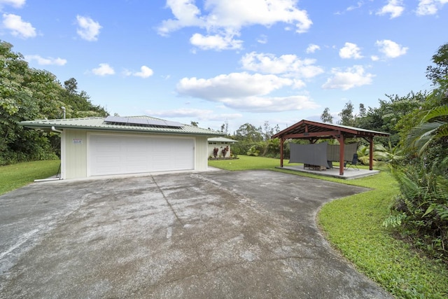 garage featuring solar panels and a lawn