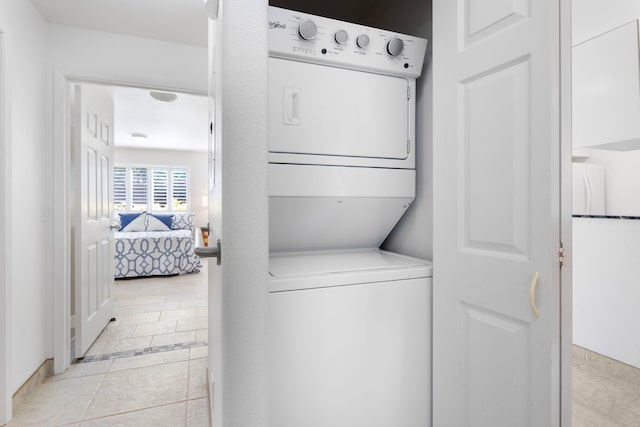 laundry area with light tile patterned floors and stacked washer and dryer