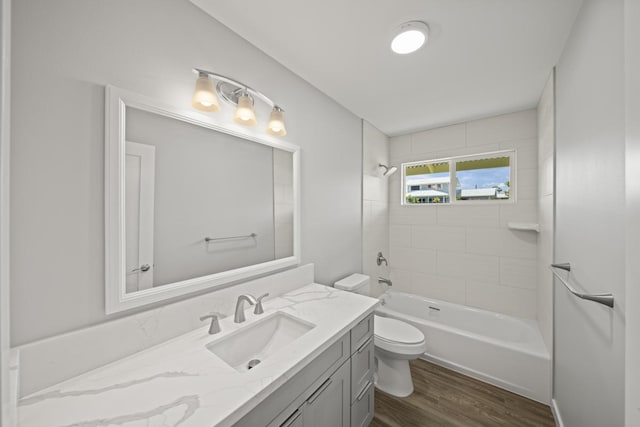 full bathroom with hardwood / wood-style flooring, tiled shower / bath combo, toilet, and vanity