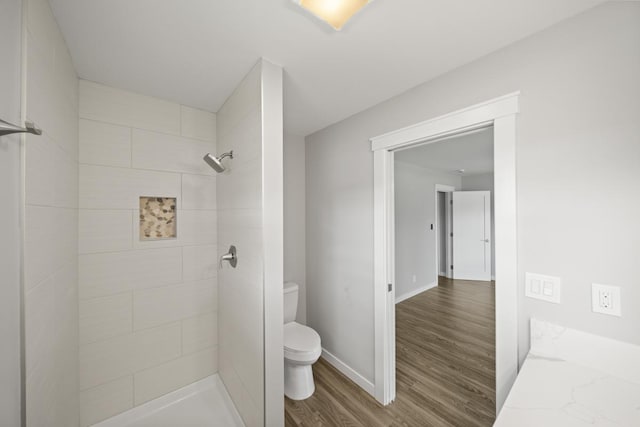 bathroom featuring tiled shower, hardwood / wood-style floors, and toilet