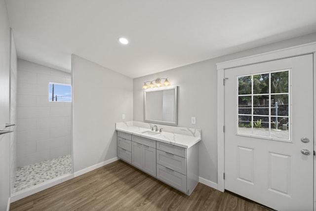 bathroom featuring hardwood / wood-style floors, vanity, a tile shower, and lofted ceiling