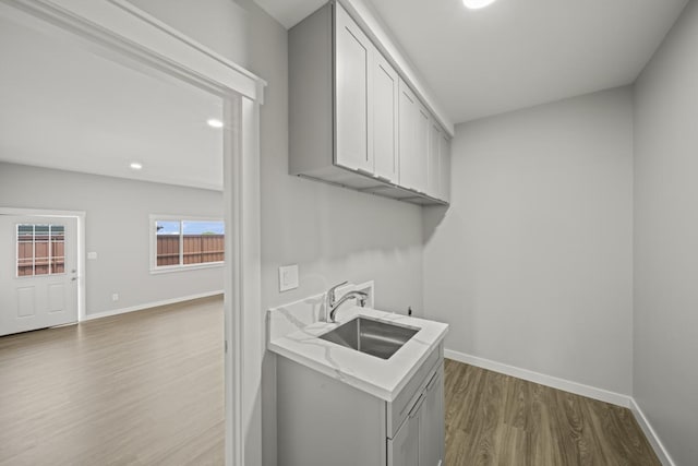 clothes washing area with washer hookup, cabinets, wood-type flooring, and sink