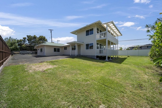 back of property with a yard and a balcony