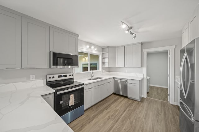 kitchen featuring light stone countertops, appliances with stainless steel finishes, gray cabinetry, sink, and light hardwood / wood-style floors