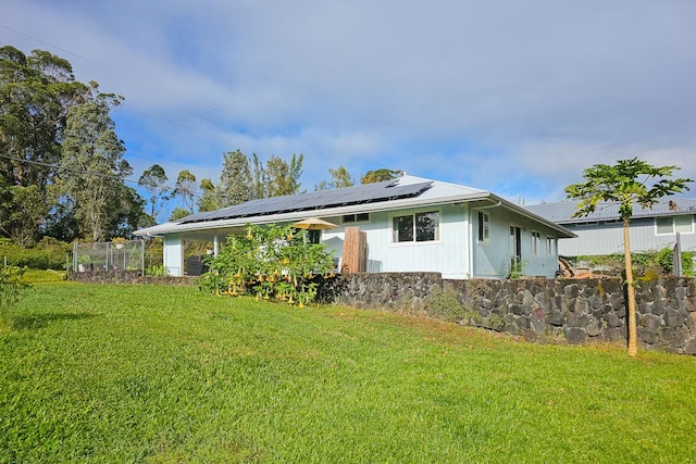 rear view of house with a yard and solar panels