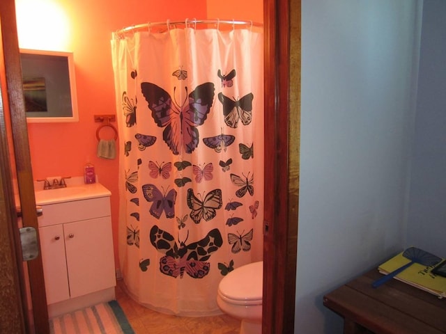 bathroom featuring tile patterned flooring, vanity, toilet, and walk in shower