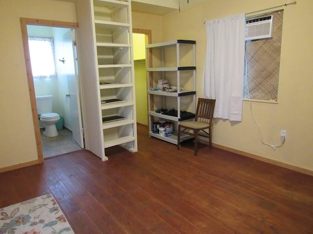 unfurnished bedroom featuring a wall mounted air conditioner, ensuite bathroom, and dark wood-type flooring