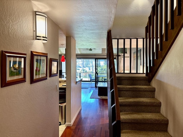 stairs with wood-type flooring and a textured ceiling