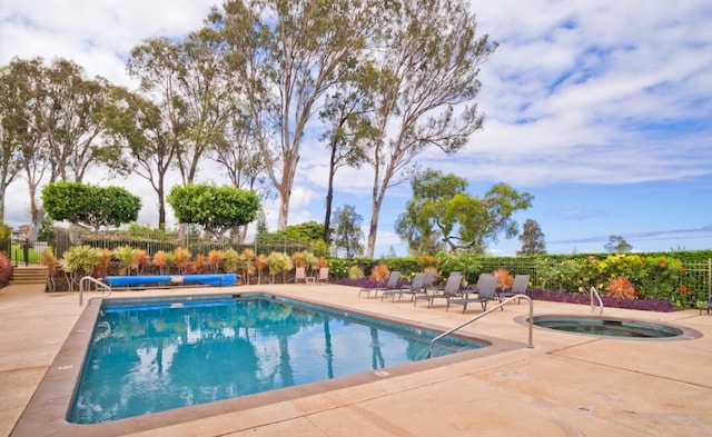 view of swimming pool featuring a patio and a hot tub