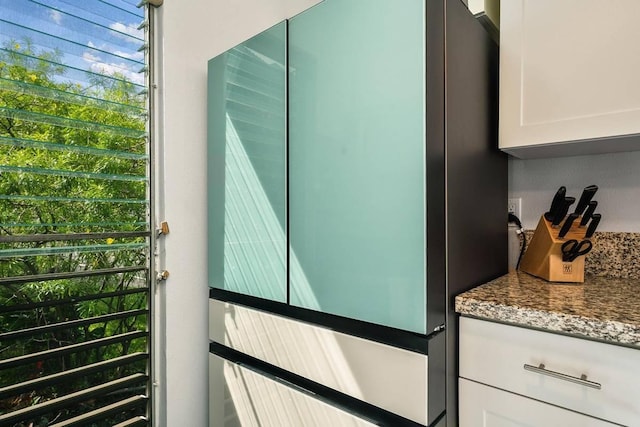 exterior details featuring white cabinets, stainless steel fridge, and stone countertops