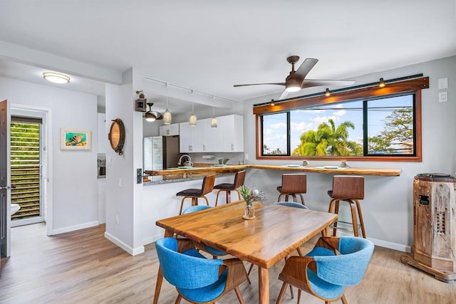 dining area with rail lighting, light hardwood / wood-style floors, ceiling fan, and a healthy amount of sunlight