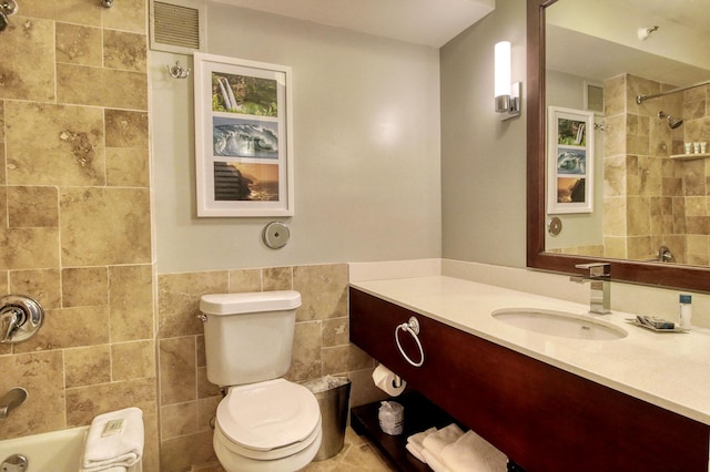 full bathroom featuring vanity, toilet, tile walls, and tiled shower / bath combo