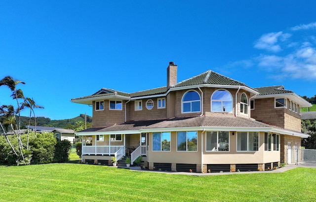 back of house featuring a lawn and covered porch