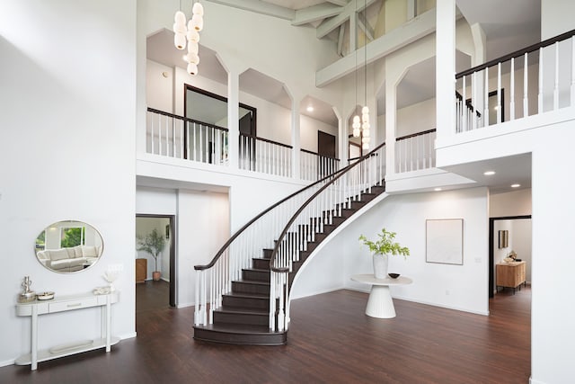 staircase with beamed ceiling, hardwood / wood-style flooring, high vaulted ceiling, and a notable chandelier