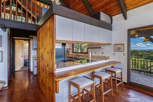 kitchen featuring white cabinetry, beamed ceiling, high vaulted ceiling, fridge, and black electric stovetop